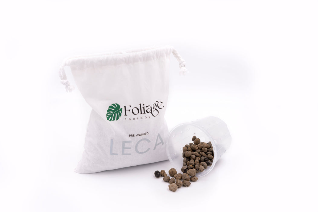 Dark clay balls spilling out of clear plastic plant pot next to Foliage Therapy calico bag