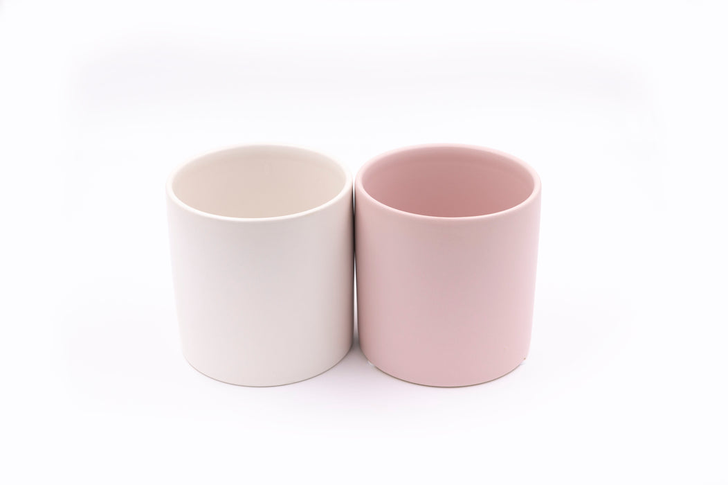 Two ceramic plant pots, one pink the other white