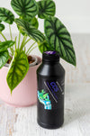 Clonex Clone Solution in black plastic bottle next to plant in pink pot